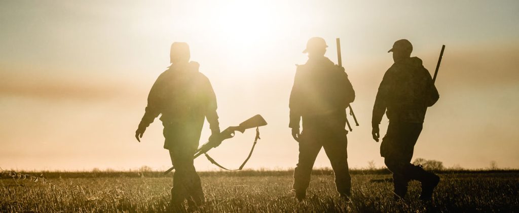 Three hunters silhouetted against the sunrise